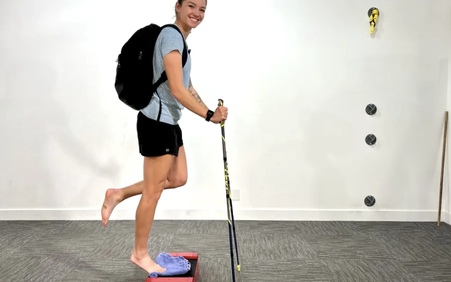 Woman training a step-up with trekking poles and a loaded backpack
