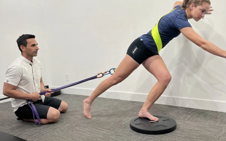 Coach assisting a resisted sprint start drill with a resistance band